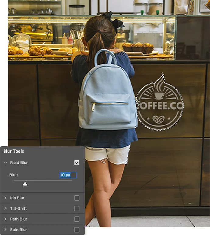 The Adobe Photoshop Blur tool settings window superimposed over a photo of a kid standing in front of a display counter that has a coffee shop's logo on it