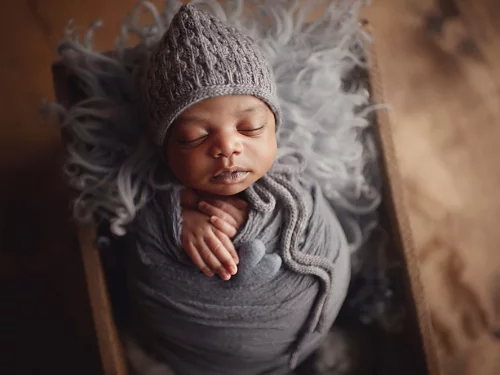 A photo of a sleeping newborn baby wearing a monochromatic outfit.