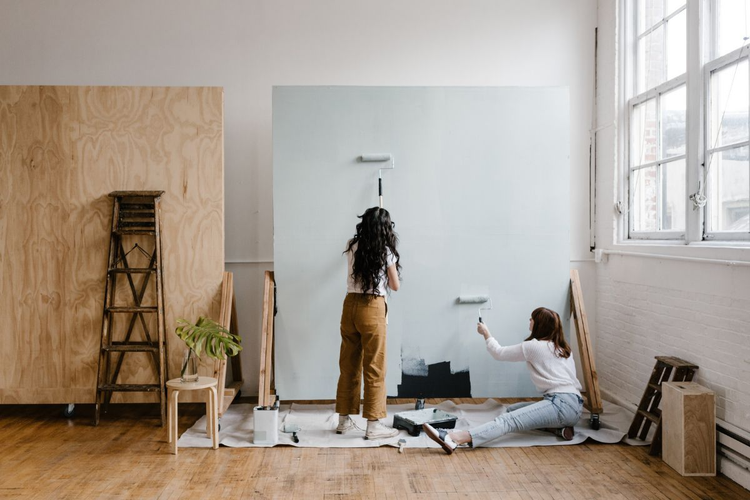 A photo of two people painting a photo backdrop.