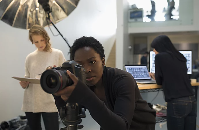 A photographer setting up their camera with a producer and photo editor working in the background