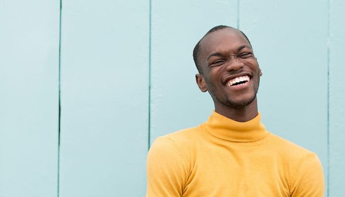 A medium close-up of someone in a turtleneck sweater laughing is created in post using Adobe Premiere Pro