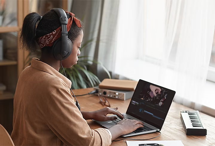 A person sitting at a desk editing a training video in Adobe Premiere Pro on their laptop