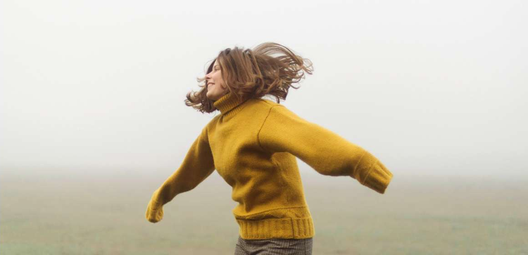 A person in a wool sweater as framed in a cowboy shot while running through a foggy field