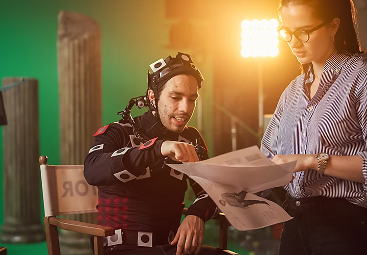 A director and a film crew member discussing the details of chroma-key for a green screen shot