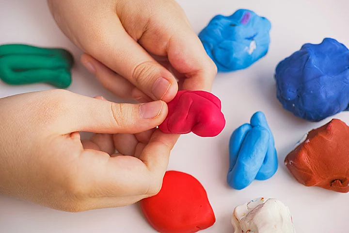 Hands moulding a small piece of clay.