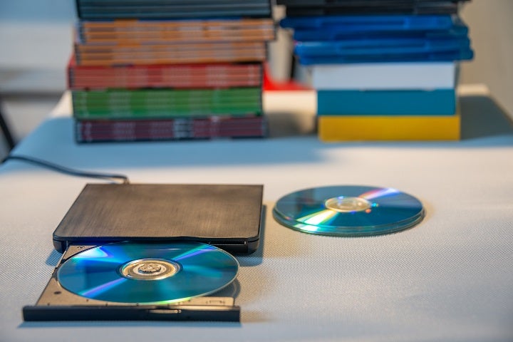DVD-Player mit eingelegter Disk, viele Disks im Hintergrund.