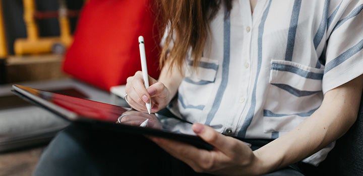 Eine Frau schreibt mit einem Eingabestift auf einem Tablet.