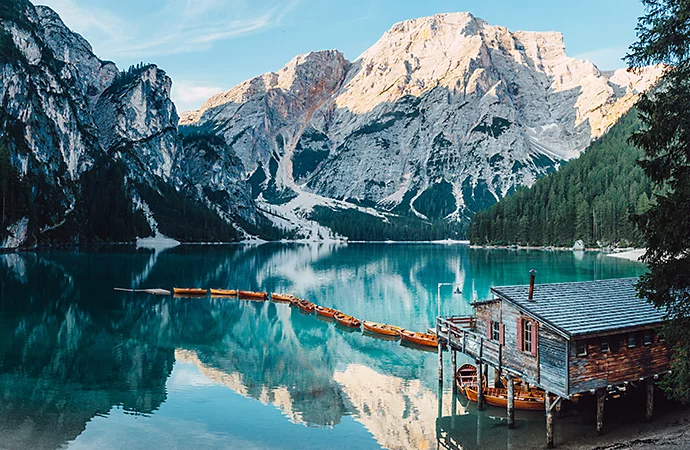 Photo of a lake house with a snow-covered mountain in the background