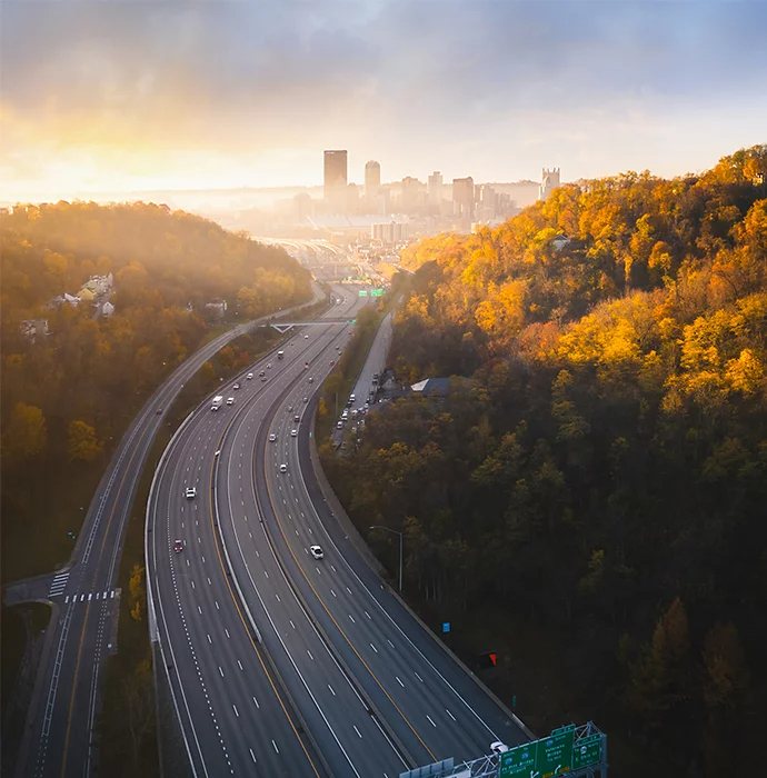 A highway running through a forest heading toward a city in the background