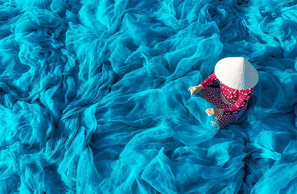 Person standing in blue fabric flowing in the wind