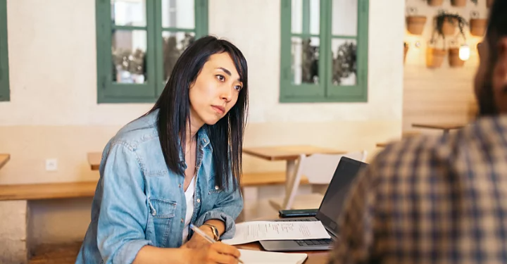 A photo of two people sitting and chatting in an office.