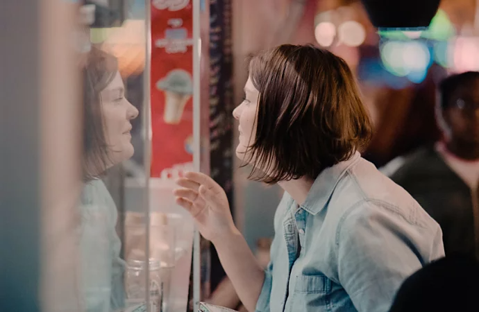 A woman looking at menu through a business's glass window