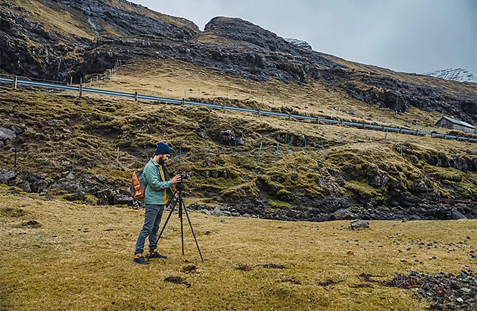 A photographer setting up a camera on a grassy hillside