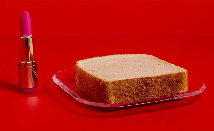 Portrait photo of bread on a plate next to an open lipstick container