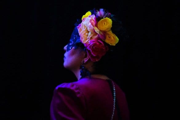 A photo of a person wearing a colorful flower headpiece at night.