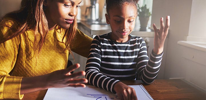 Mom helping daughter with homework in the kitchen.