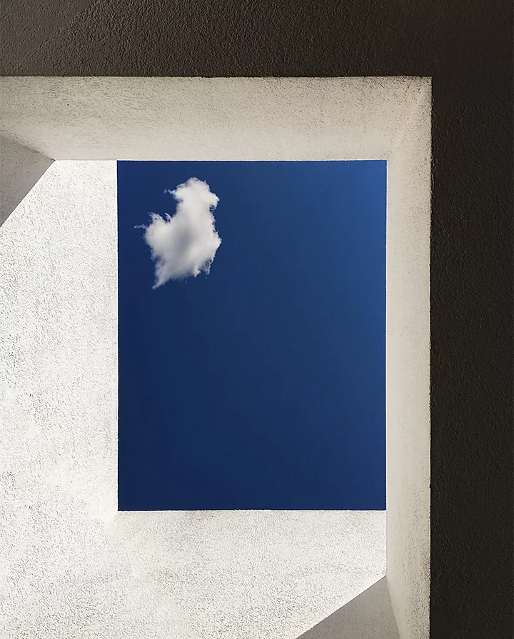 Looking straight up through a window skylight at a lone cloud in a blue sky