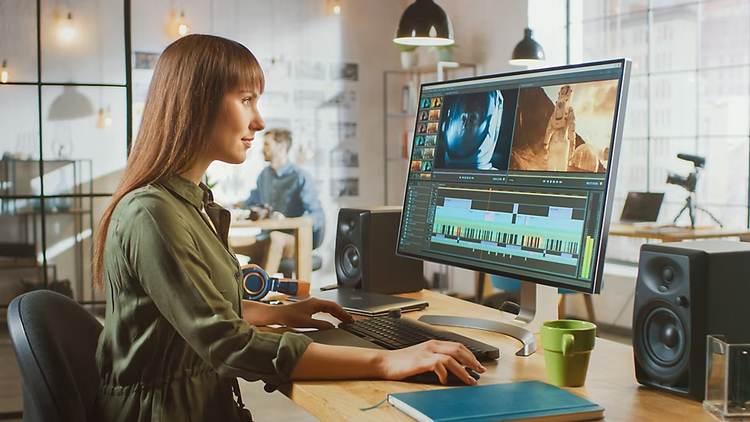 Junge Frau vor einem großen Monitor beim Filmschnitt mit Adobe Premiere Pro.