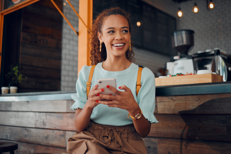 A person sitting at a counter holding a phone Description automatically generated