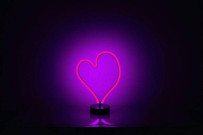 A neon heart shaped object in a dark room Description automatically generated