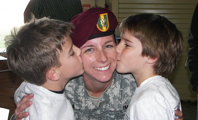 Close up of Maggie Pratt smiling in a military uniform with two children kissing each of her cheeks.