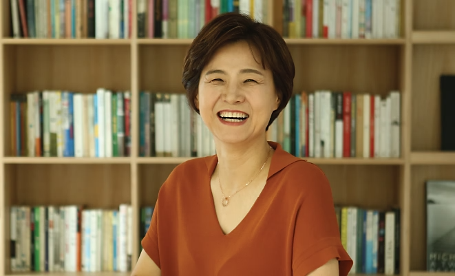 Closeup of Mary Woo smiling in front of bookshelves filled with books.