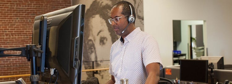 A person wearing a headset and looking at a computer screen Description automatically generated