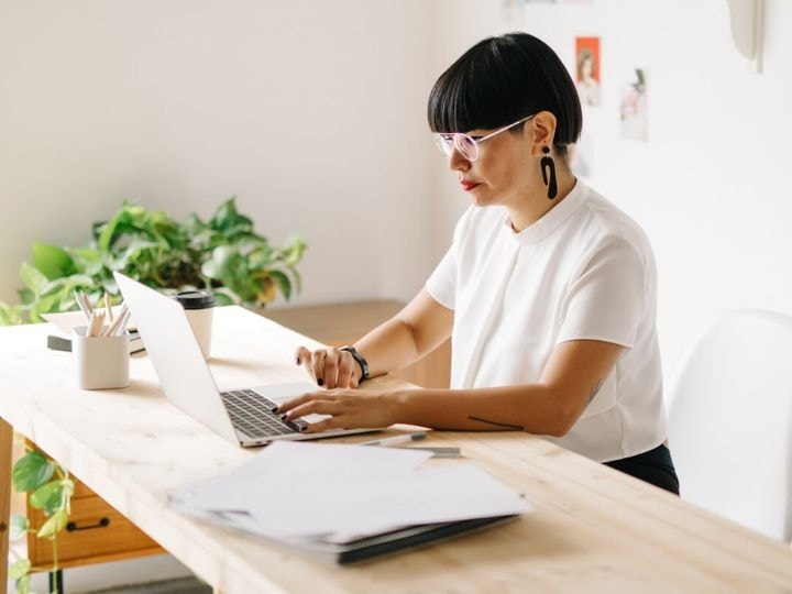 A photo of a person sitting at a desk in an office and using a laptop computer.