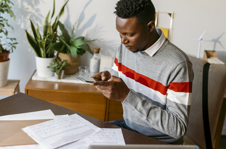 A man sitting at a desk scanning documents with their mobile phone.