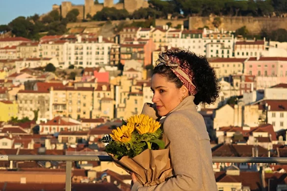 A photo of a person holding flowers with a city view in the background.