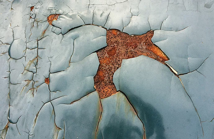 Close-up of an industrial building wall with paint peeling and cracking off of it