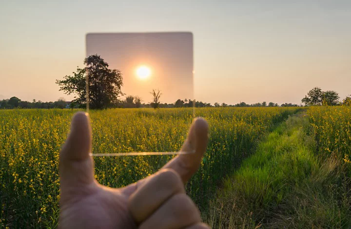 An ND filter held up to block the sun for a photo of a prairie