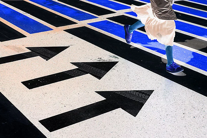 A colour-inverted photo of lines on a footpath and a person walking over them