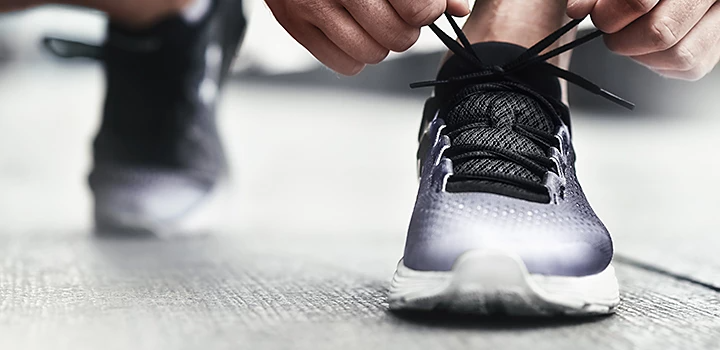 A close-up photo of hands tying shoelaces.