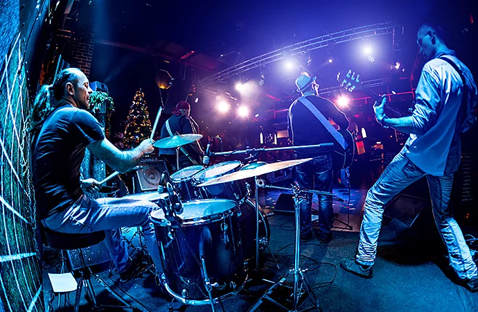 A behind-stage view of a band playing on stage pointing toward the audience