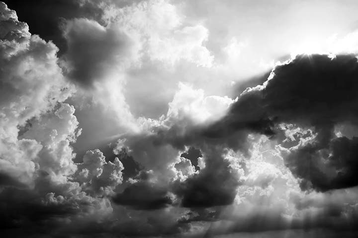 Imagen en blanco y negro de la luz del sol traspasando un banco de nubes.