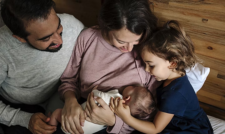 Una familia mirando a su hijo recién nacido para una foto familiar