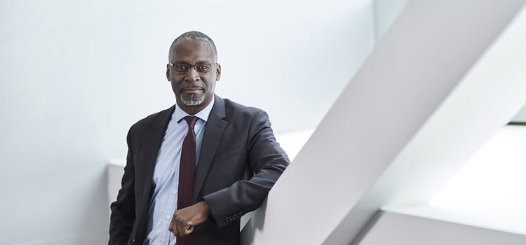 A person posing and leaning against a column for a corporate headshot photo