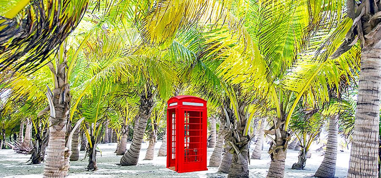 Imagen compuesta de una cabina telefónica en medio de la playa.