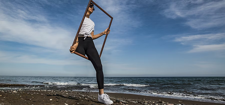 Imagen compuesta de una mujer saliendo de un marco en la playa.