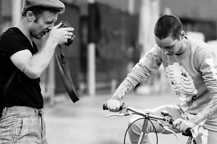 Fotografía en blanco y negro de un fotógrafo que le toma una foto a una persona montada en una bicicleta