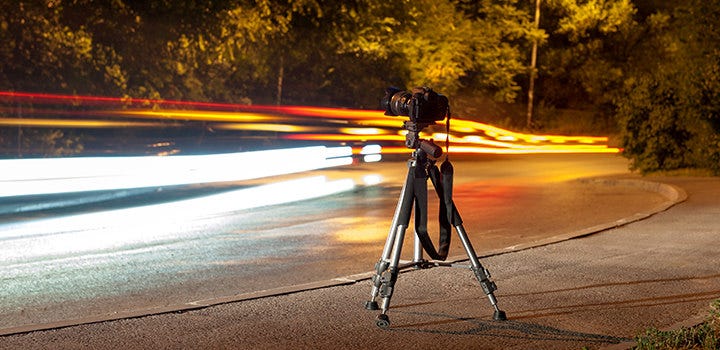 Long exposure photo of car headlights and taillights in the street with tripod in foreground.