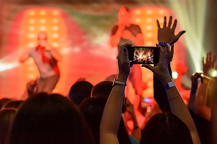 Imagen de una persona tomando una fotografía con su móvil en un concierto.