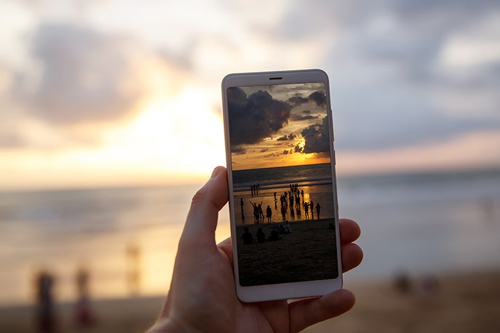 Imagen de una persona tomando una fotografía del atardecer en su teléfono móvil.