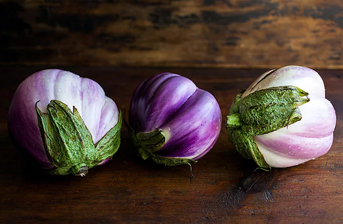 Three Indian eggplants on a wooden table