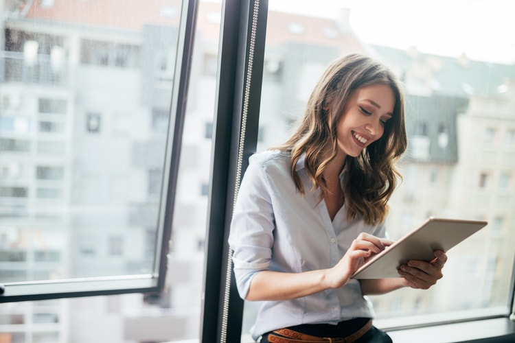 Woman standing by the windows while using her tablet