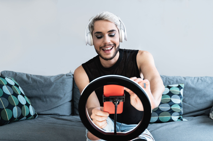 Filming a tiktok A man is seen wearing white headphones, in front of a ring light with a phone attached