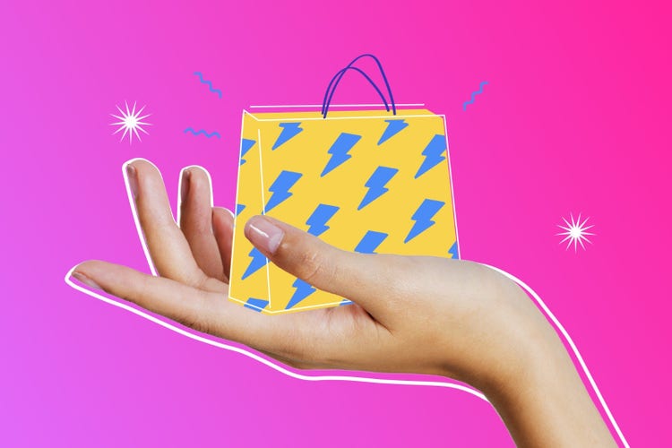 An outstretched hand holding a graphic of an Etsy shopping bag against a pink background