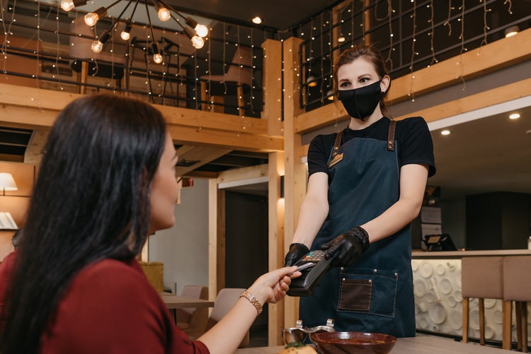 How to go Contactless (for businesses): waitress handing a wireless payment terminal to a customer