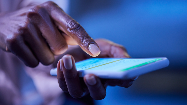 A finger hovers above a lit phone screen.